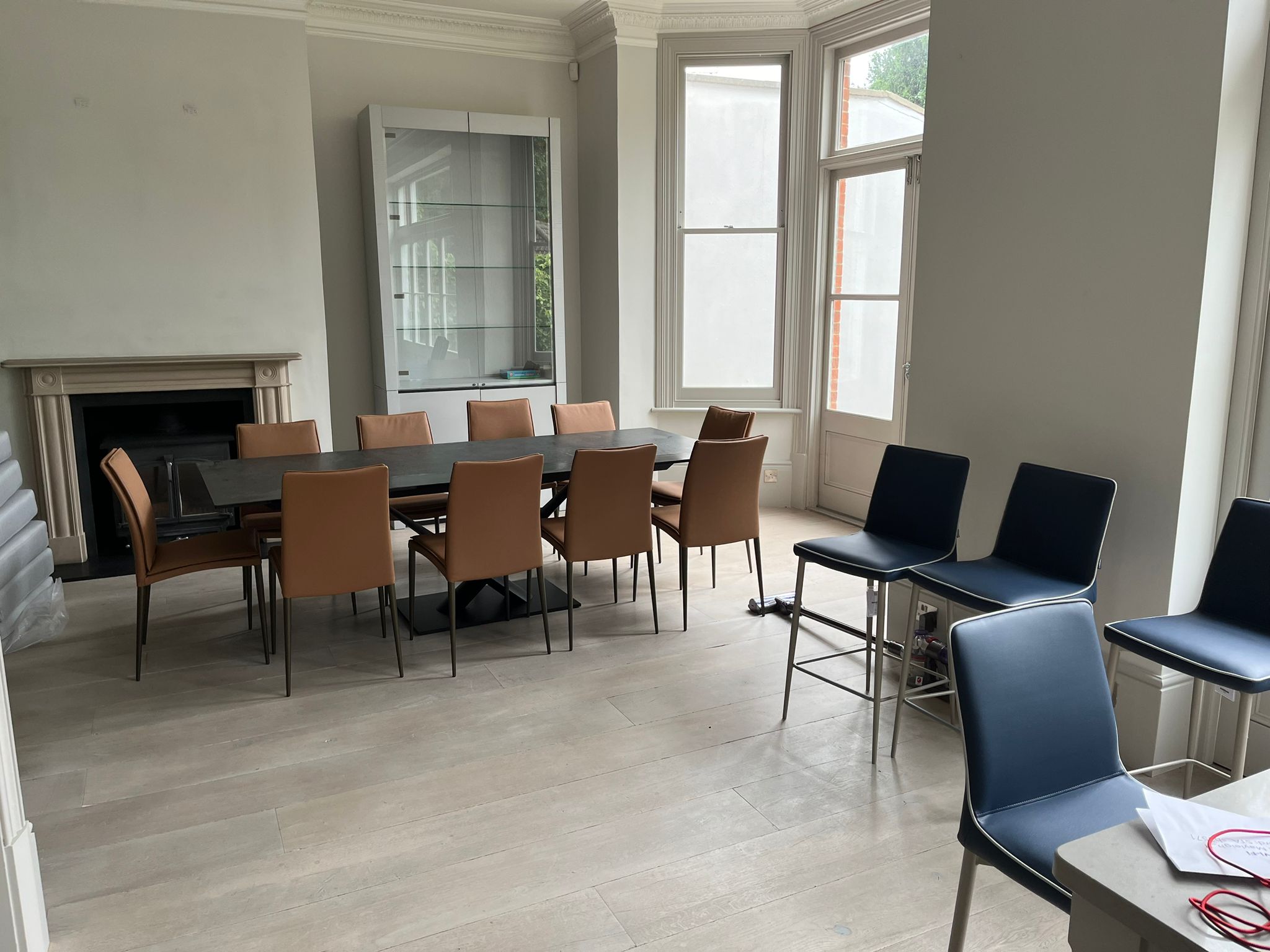 Georgian dining room featuring tan leather dining chairs around a dark slate dining table with contrasting navy leather bar stools - FCI London client project demonstrating intentional colour contrast within a shared material language